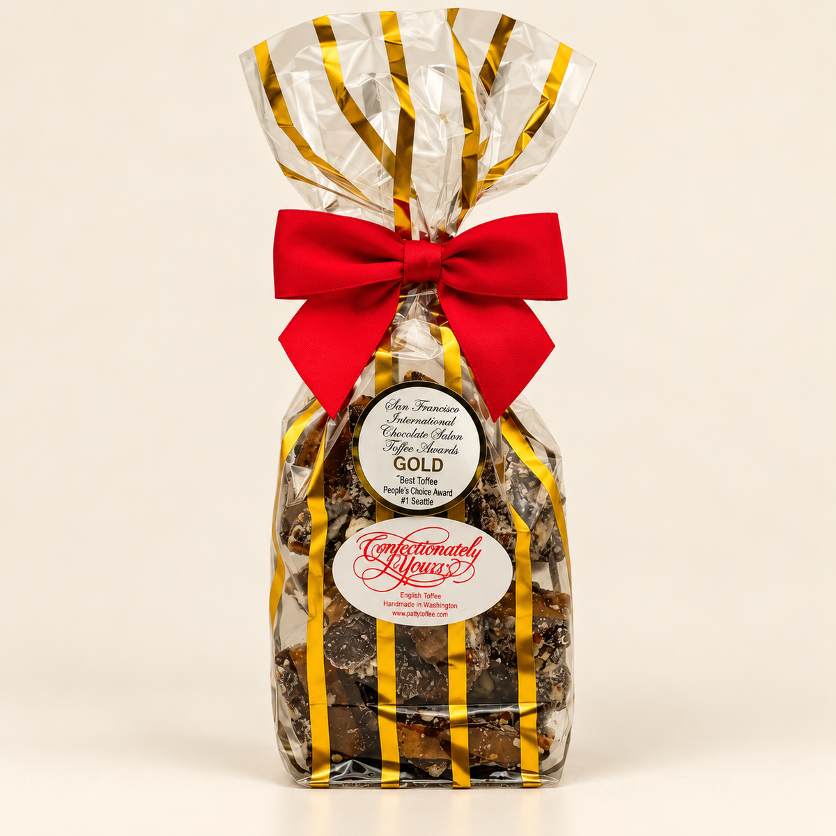 Half-pound Confectionately Yours dark chocolate almond English toffee in gold-striped holiday packaging with red bow.