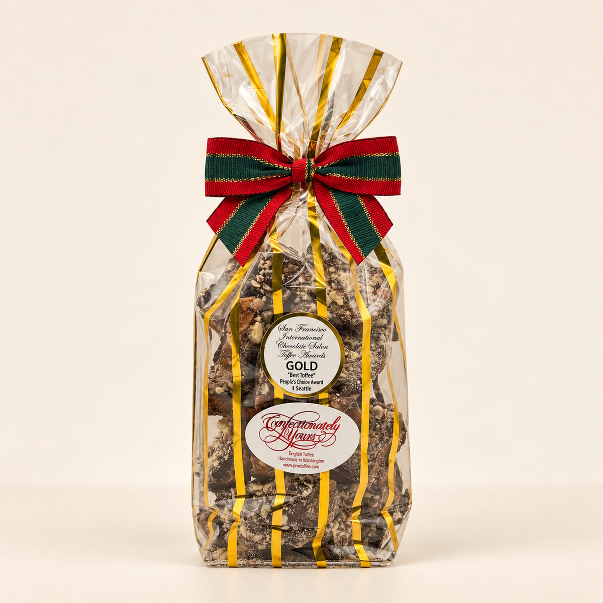 One-pound Confectionately Yours dark chocolate almond English toffee in gold-striped holiday packaging with festive bow