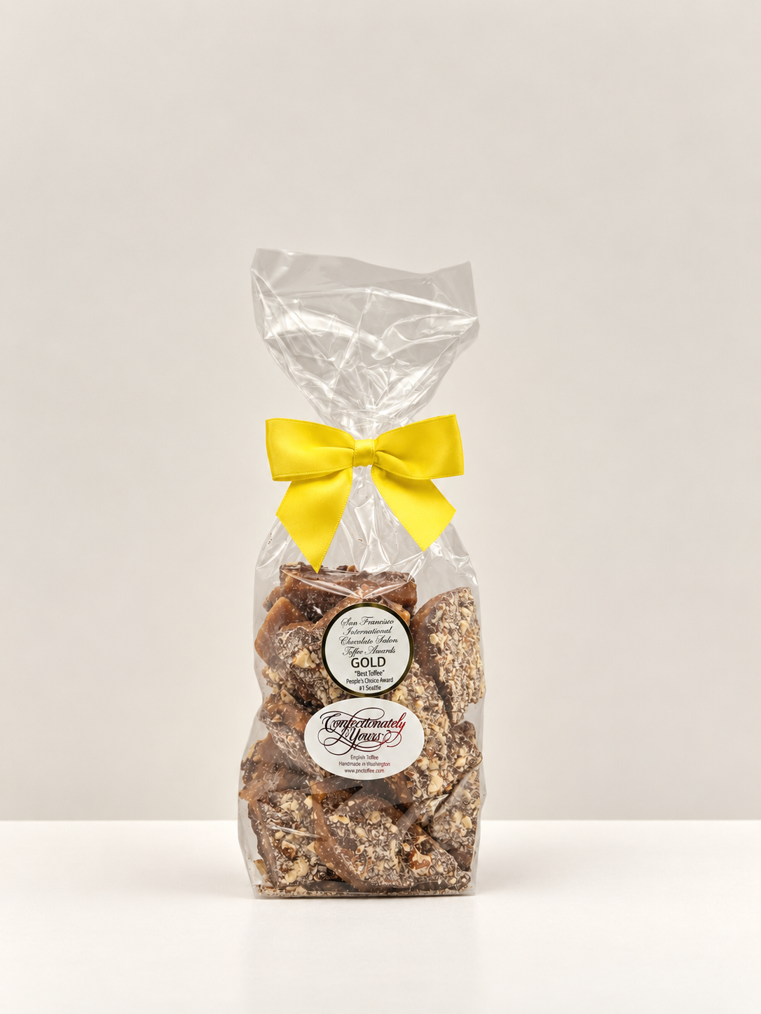 One-pound Confectionately Yours milk chocolate almond English toffee in a clear gift bag with yellow bow