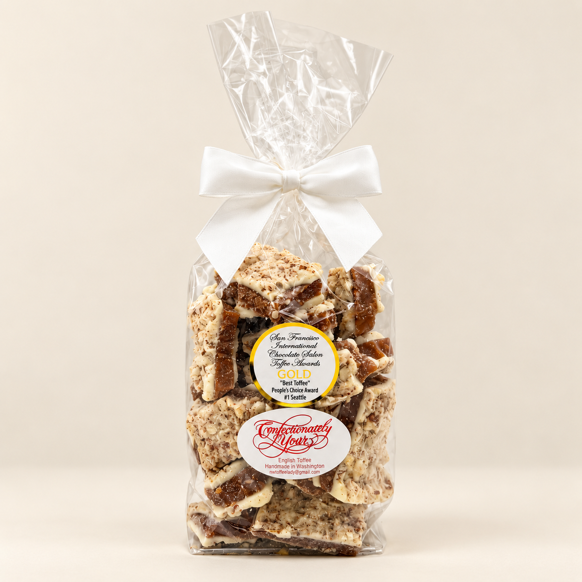 One-pound Confectionately Yours white chocolate almond English toffee in a clear gift bag with white bow
